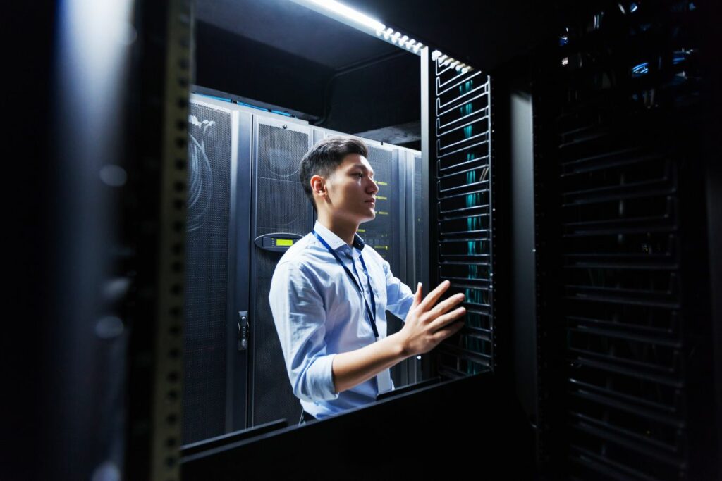 Technician meticulously inspecting server cabinets in a data center.