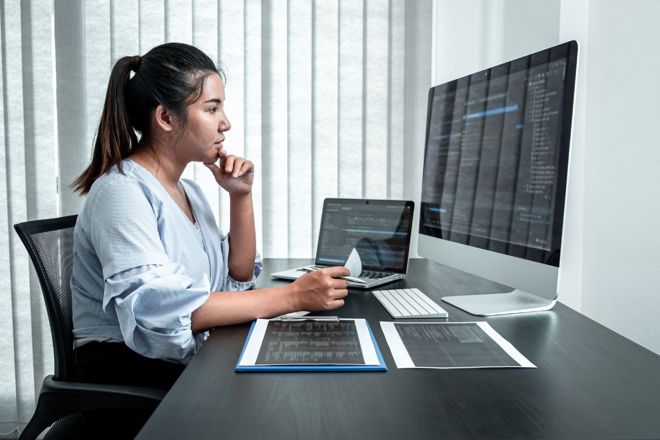 Woman performing a Technology Risk Assessment on multiple screens in a it consulting office environment.