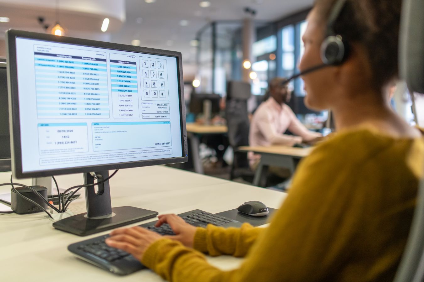 Customer service representative working at a computer with headphones in an office environment, providing Technical Support.