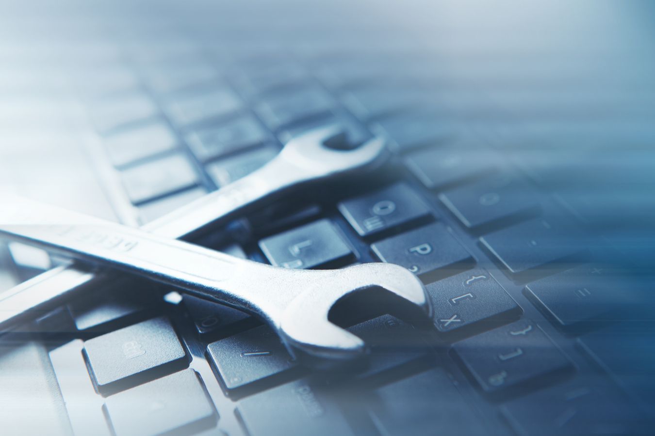 A wrench lying on a laptop keyboard, suggesting proactive maintenance & operations or IT support.