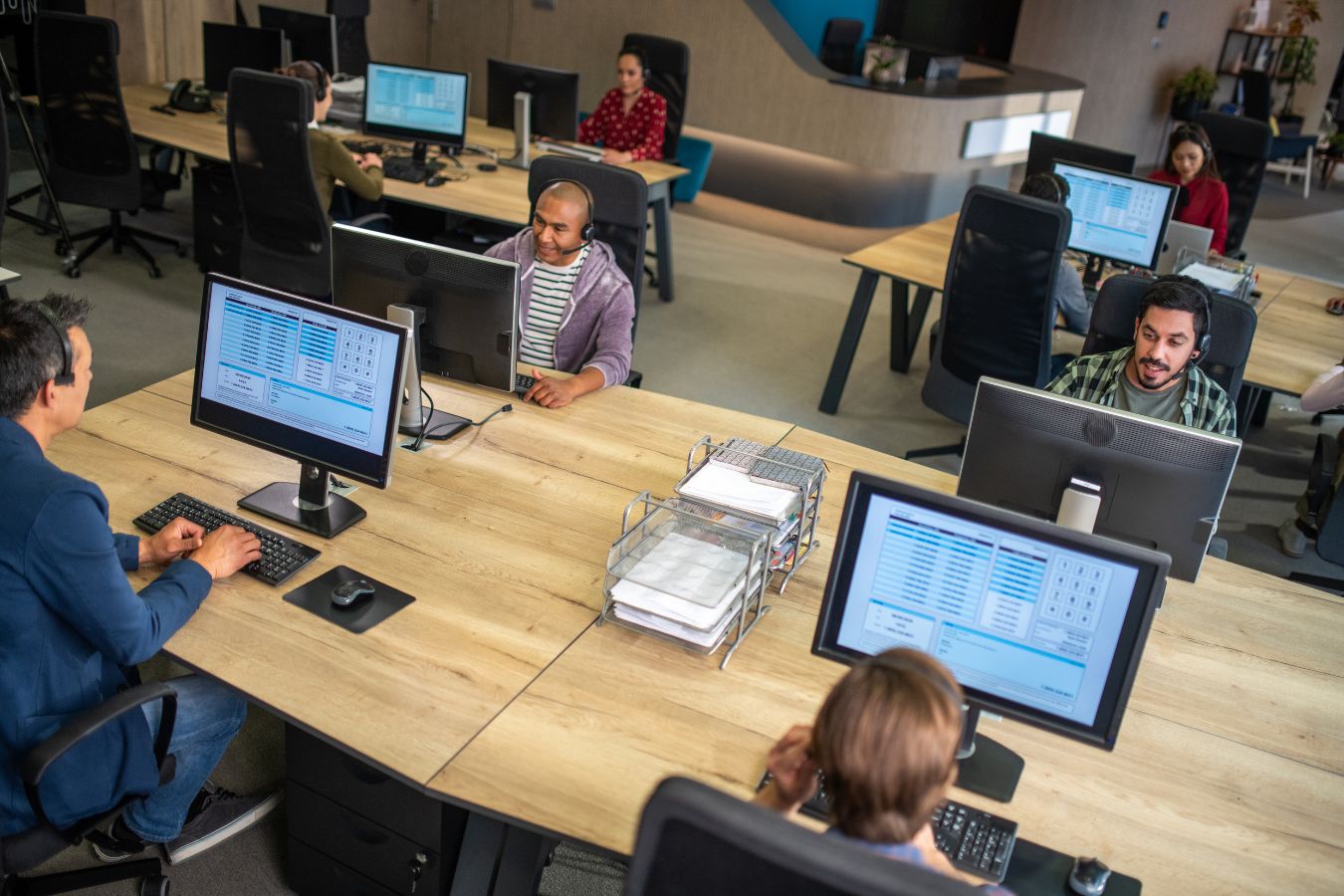 Professionals providing IT Support working on computers in a modern open-plan office.