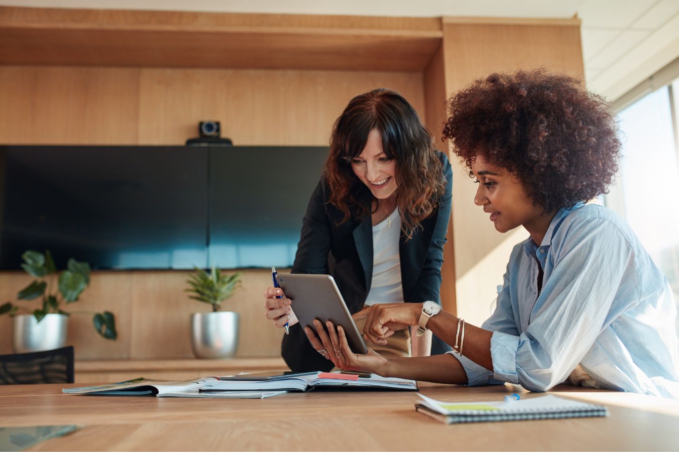 Two colleagues discussing staffing work on a tablet in a modern office setting.